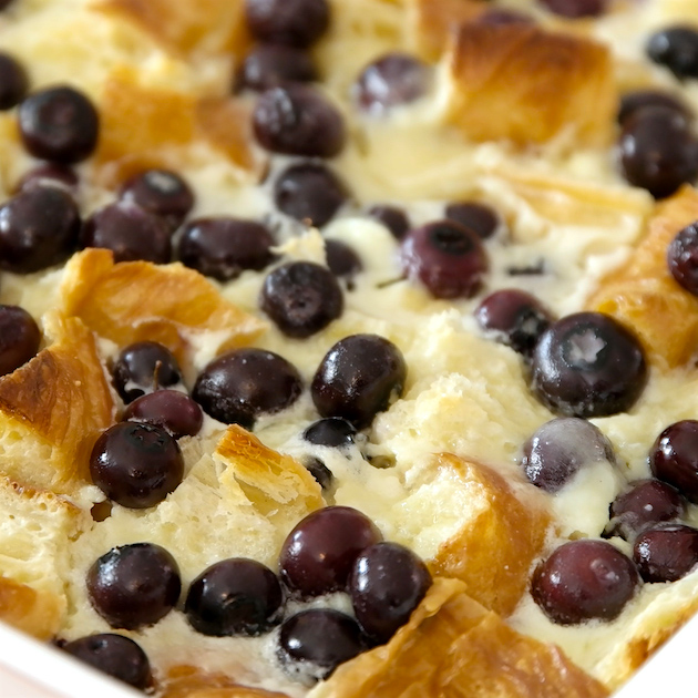 Blueberry bread pudding in a baking dish after coming out of the oven showing plump blueberries and a golden bread pudding surface
