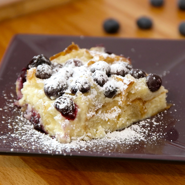 Blueberry Bread Pudding dusted with powdered sugar and served on a plate for a mouthwatering breakfast, brunch or dessert