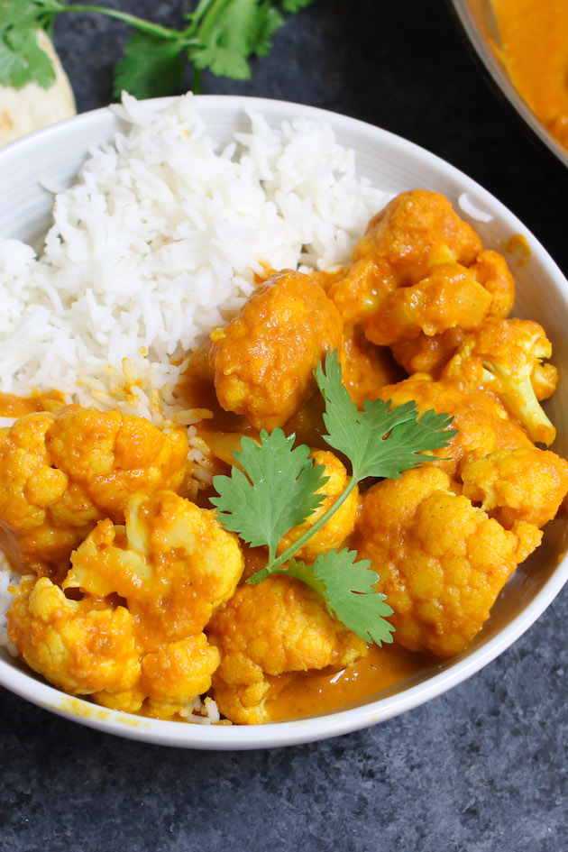 Cauliflower curry served on rice in a white bowl