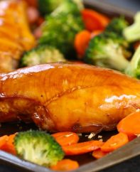Cooked chicken breast on a sheet pan after being baked with vegetables