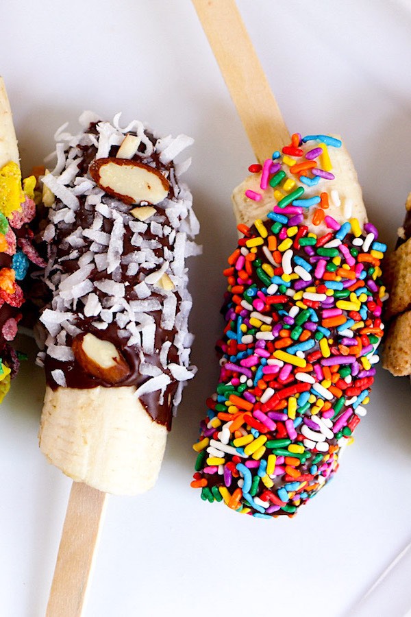 Chocolate Covered Bananas are the easiest snacks ever! Just 3 ingredients: banana, chocolate and coconut oil, plus whatever toppings you like such as crushed M&Ms, fruity pebble cereal, cinnamon toast crunch and colored sprinkles. Beautiful and irresistibly delicious! Quick and easy recipe. Kids friendly. Video recipe. | Tipbuzz.com #ChocolateCoveredBananas #ChocolateBananas
