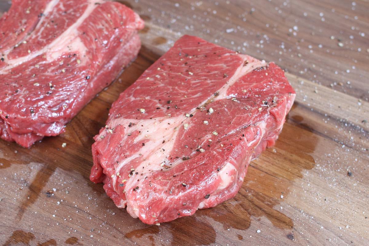 Chuck steak seasoned with salt and pepper, ready for cooking