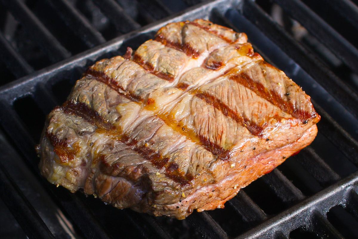 Chuck eye steak cooking on the grill with beautiful grill marks on top