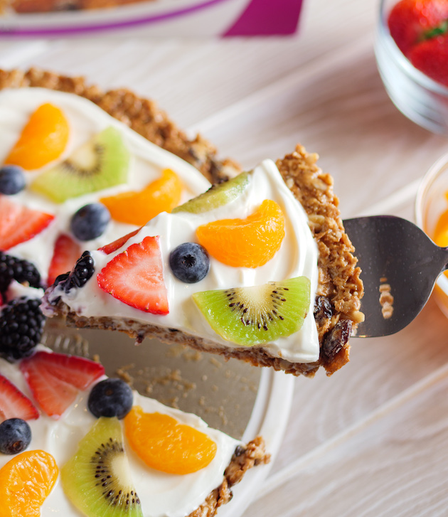 This photo shows lifting a piece of Raisin Bran Fruit Pizza to a serving plate