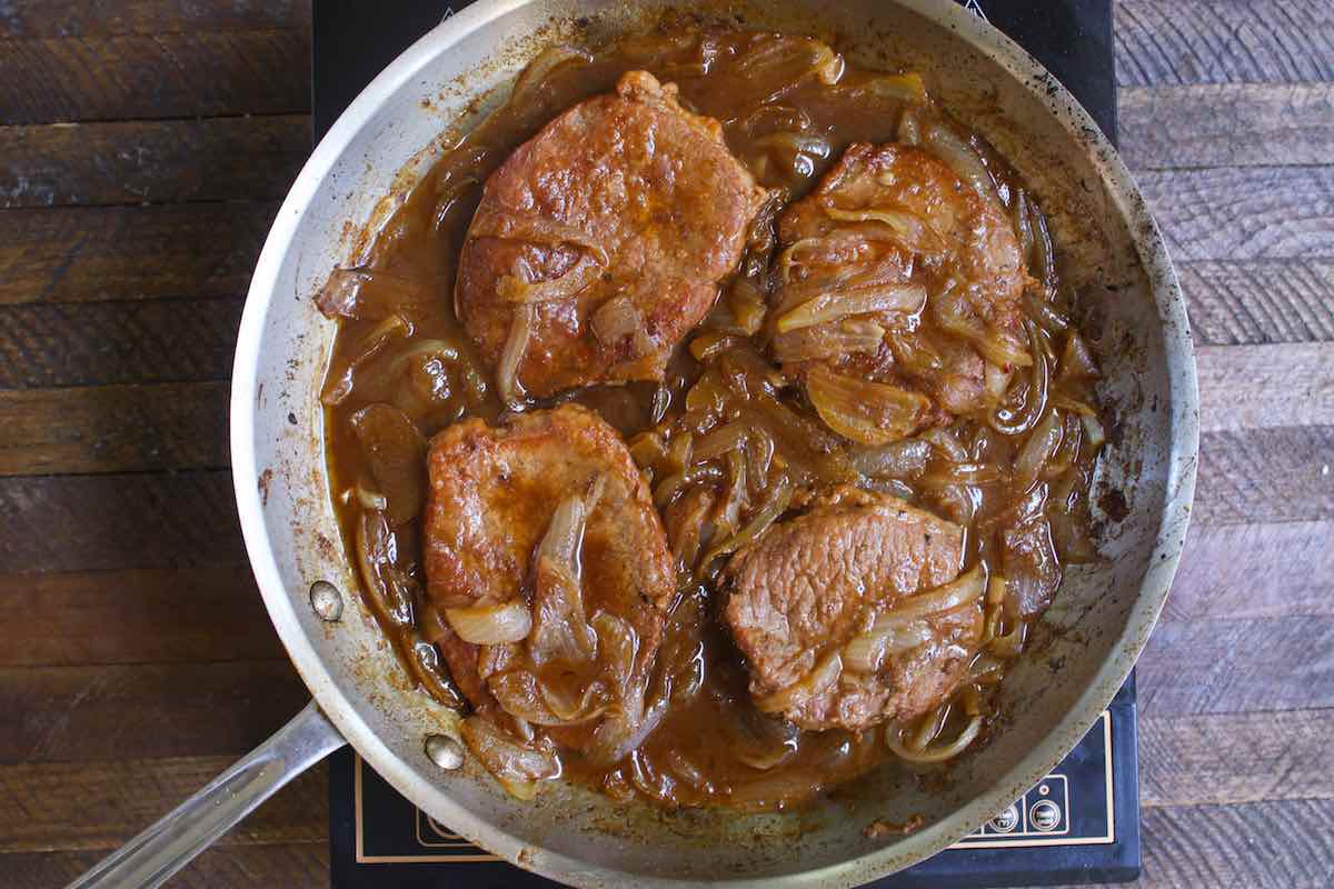 Braised eye of round steaks in a pan. 
