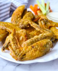 Crispy baked chicken wings on a serving platter with carrots, celery and ranch dip