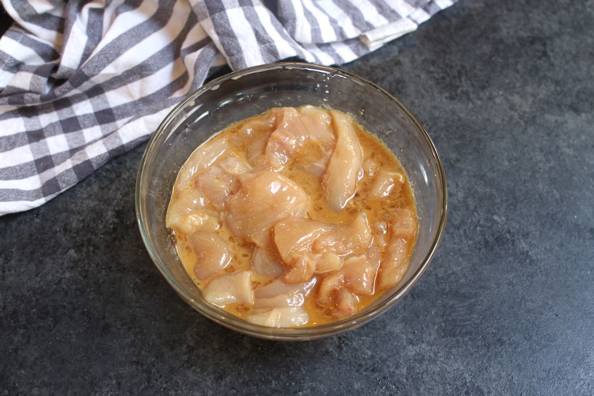 Sliced chicken breast marinating in rice vinegar, egg white and cornstarch when making Hunan Chicken
