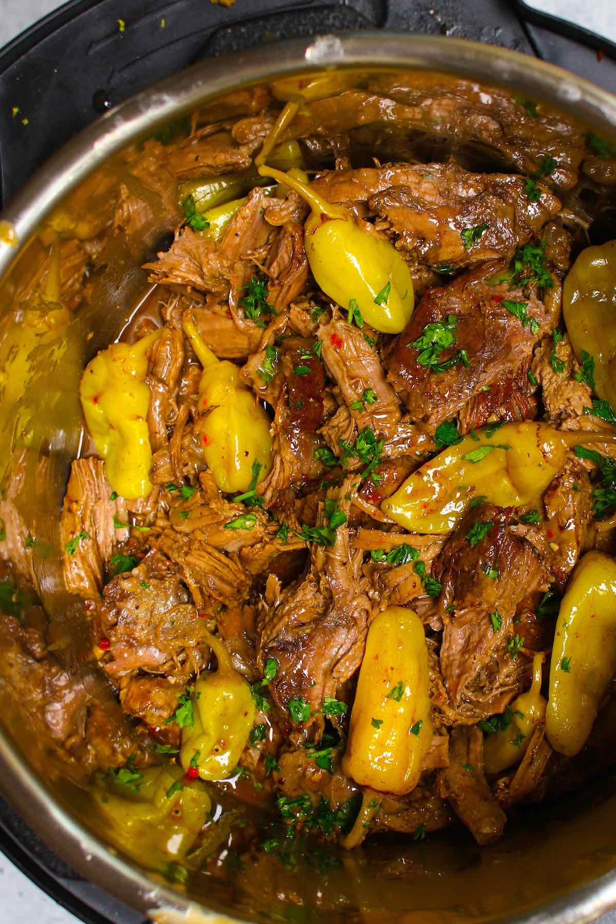 Cooked Mississippi pot roast in a slow cooker, sprinkled with chopped parsley.