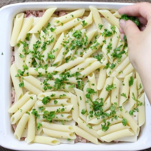 Making Layered Pasta Bake with ham and penne pasta, adding fresh parsley on top before baking