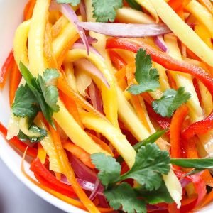 Mango Salad in a serving bowl for a quick summer salad recipe that everyone always loves! A rich and creamy Peanut Dressing is tossed with fresh mango, carrots, red bell pepper, red onions and crunchy peanuts to give you the most refreshing salad