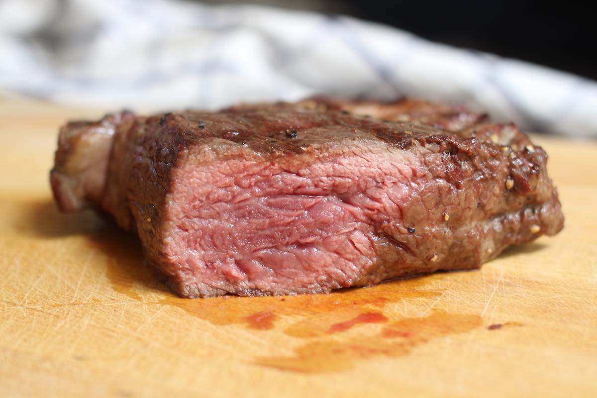 Closeup of steak grilled medium rare so it's nicely seared on the outside with a warm red center