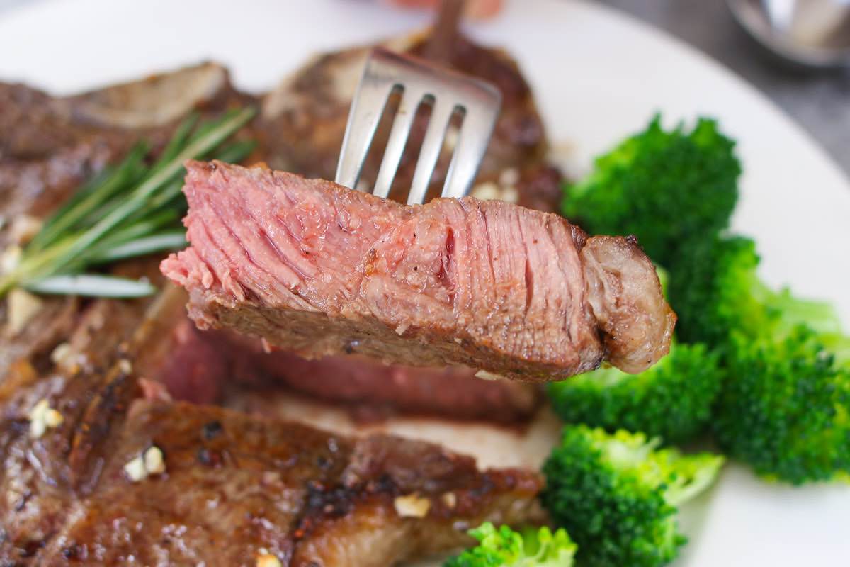 Closeup of steak grilled medium so the outside is fully seared and the inside is pale pink