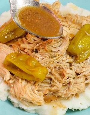 Spooning juices from the slow cooker onto the shredded chicken