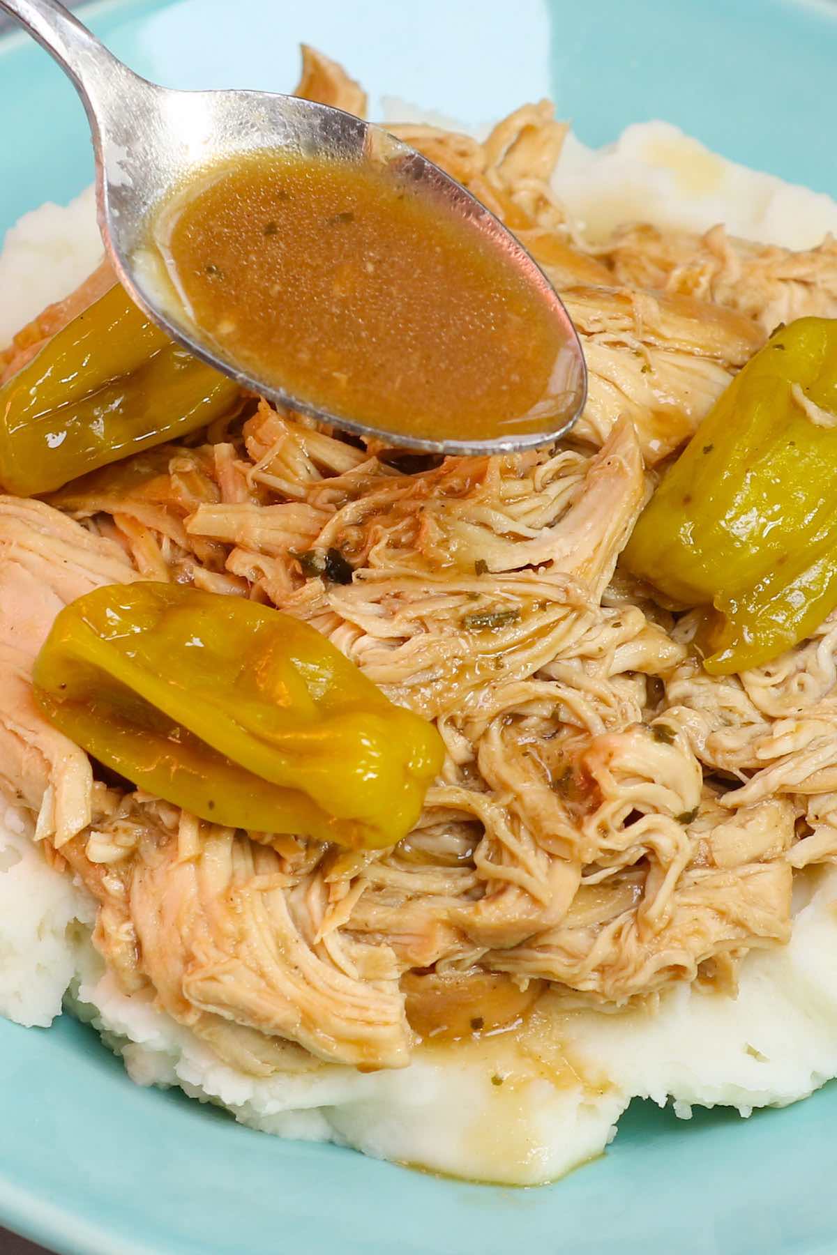 Spooning juices from the slow cooker onto the shredded chicken