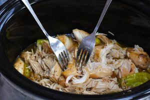 Shredding chicken breasts with two forks before serving
