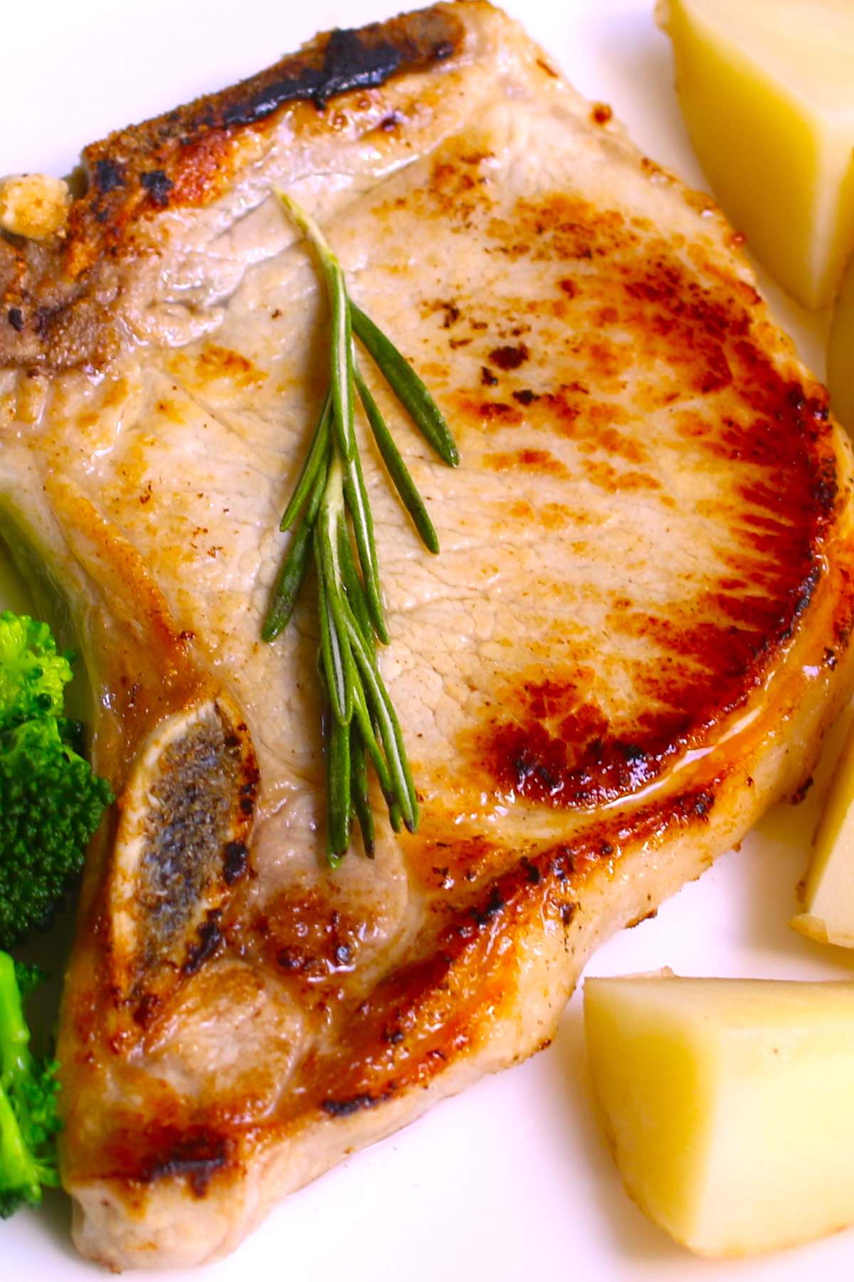 Pork chop served with potatoes and broccoli on a white plate.