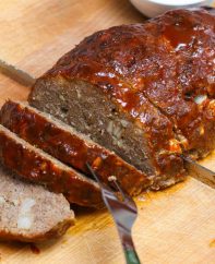 Perfect smoked meatloaf being sliced on a carving board