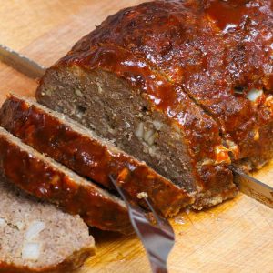 Perfect smoked meatloaf being sliced on a carving board