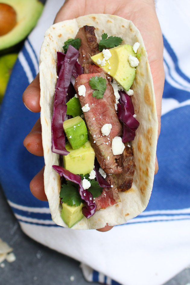You can make steak tacos on the grill or stovetop - this photo shows a simple grilled steak taco held in the hand