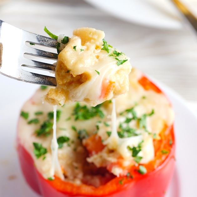 Closeup of a cheese pull on a red stuffed bell pepper with a fork