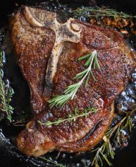 T-bone steak searing in a hot cast iron skillet